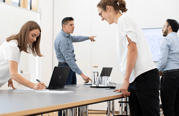 Mitarbeiter halten einen Workshop ab, Dokumente und Laptops liegen auf einem Tisch